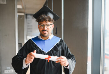 Smiling arab student wearing a graduation gown and holding a diploma, celebrating academic achievement with pride and joy